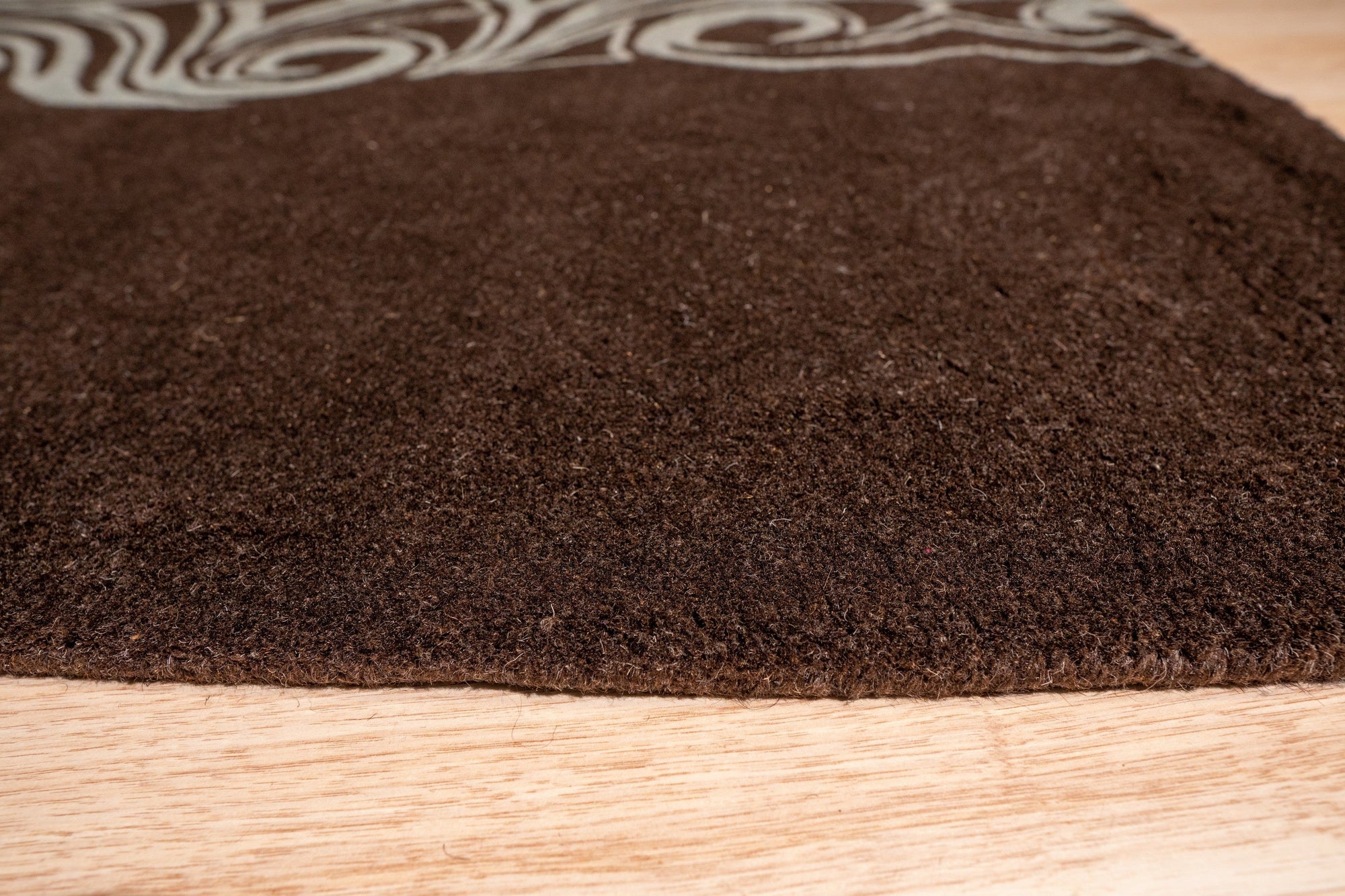 Yara Para Brown Hand Tufted Wool Rug, its warm, earthy tones anchoring a modern living room. Subtle variations in the brown wool create a rich, textured surface under a low coffee table, inviting barefoot comfort.