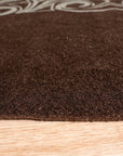 Yara Para Brown Hand Tufted Wool Rug, its warm, earthy tones anchoring a modern living room. Subtle variations in the brown wool create a rich, textured surface under a low coffee table, inviting barefoot comfort.