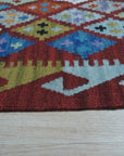 Amara Kilim Multicolor Flatweave Wool Rug, showcasing its vibrant geometric patterns and flatweave construction, displayed in a bright living room setting.