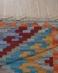 Iris Sophisticated Multicolor Flatweave Wool Rug displayed in a bright, modern living room; its vibrant geometric pattern anchors the space beneath a sleek coffee table and minimalist sofa.