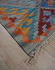 Iris Sophisticated Multicolor Flatweave Wool Rug, showcasing a vibrant geometric pattern in shades of blue, orange, red, and cream, laid flat with a subtle sheen on its wool fibers.