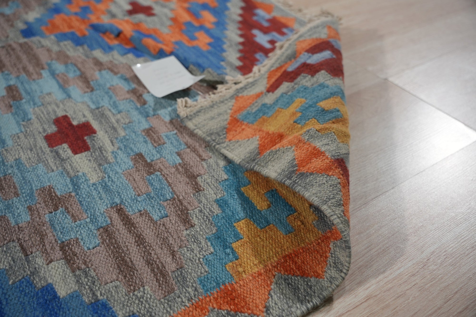 Iris Sophisticated Multicolor Flatweave Wool Rug, showcasing its vibrant palette and intricate flatweave construction in a modern living space. Warm sunlight highlights the rug's textural details and rich color variations.