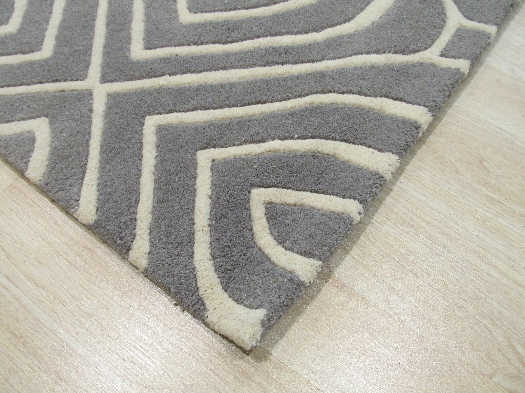 Beautiful Luna Gray Hand Tufted Wool Rug, showcasing its soft gray hues and hand-tufted texture, laying flat on a light surface suggesting a cozy and inviting atmosphere.