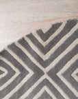 Beautiful Luna Gray Hand Tufted Wool Rug, its soft gray tones and plush wool texture inviting touch and warmth, lies elegantly on a light wood floor.