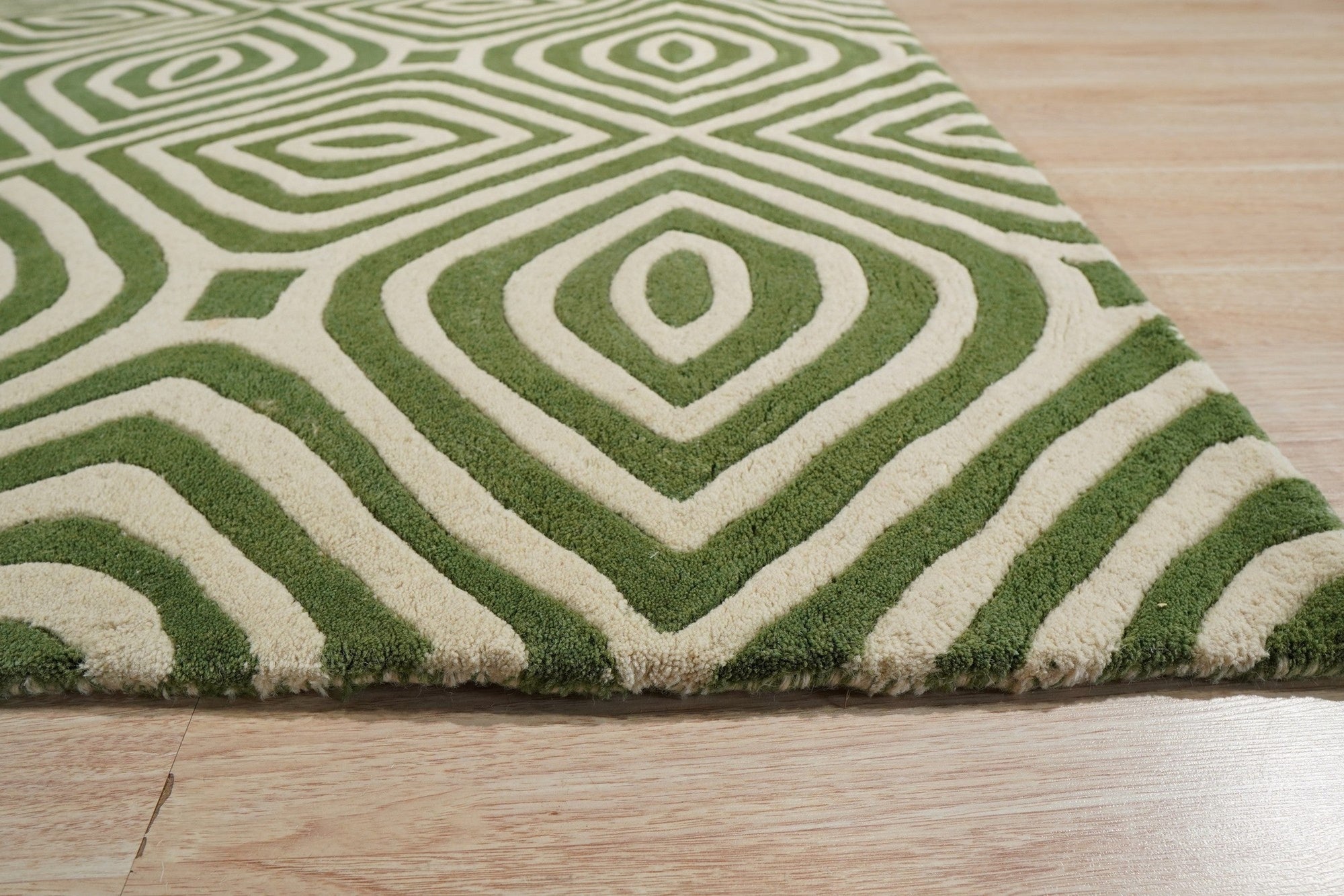 Zinnia Amara Green Hand Tufted Wool Rug displayed, its textured green wool pile a captivating blend of depth and comfort within a softly lit interior.