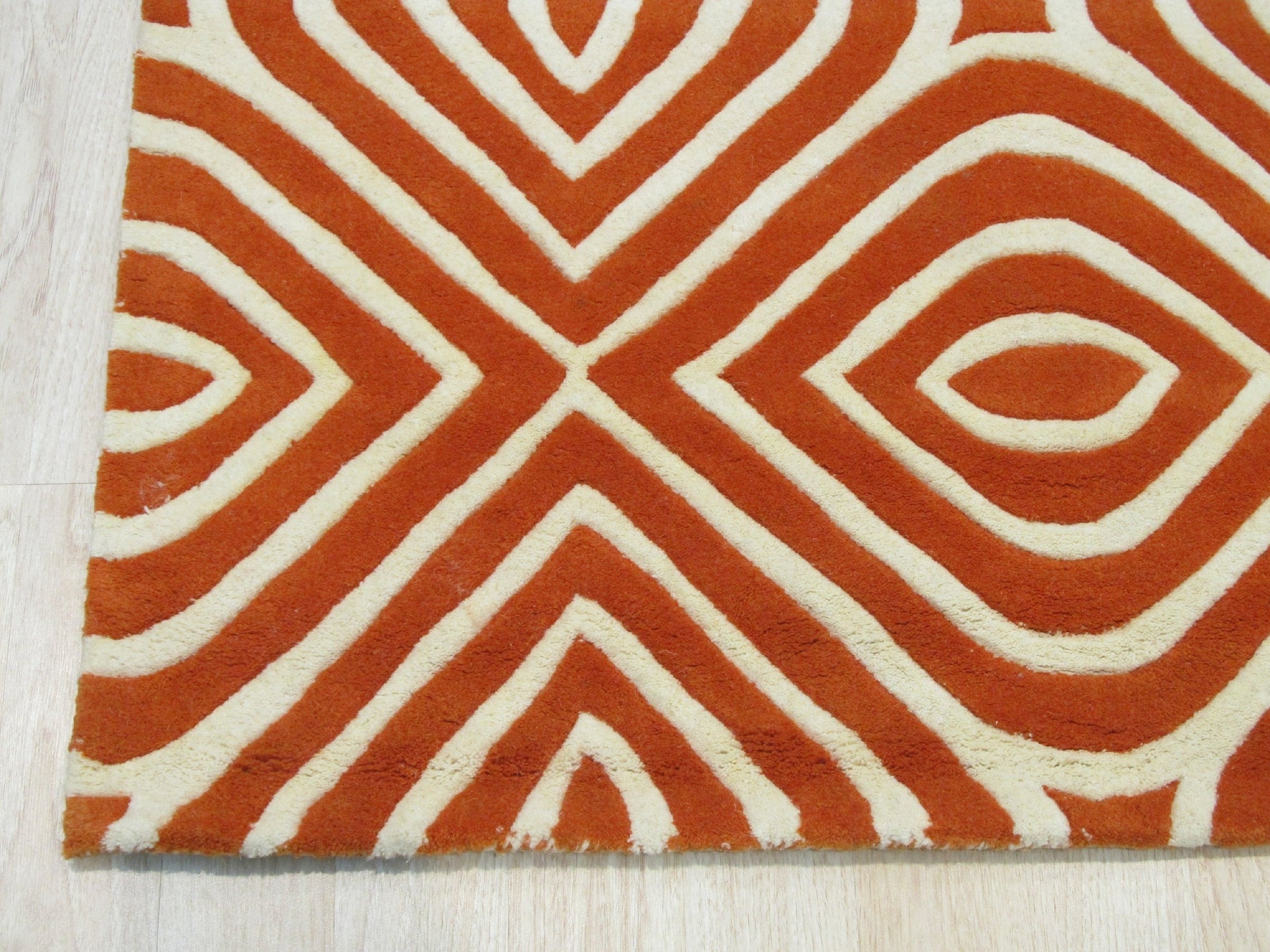 Luxurious Warm Orange Hand Tufted Wool Rug, its rich orange tones and plush, hand-tufted texture anchoring a modern living room with light wood flooring and neutral furniture.