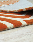 Luxurious Warm Orange Hand Tufted Wool Rug, seen in a warmly lit room, its plush texture and vibrant orange hues creating a cozy and inviting atmosphere.
