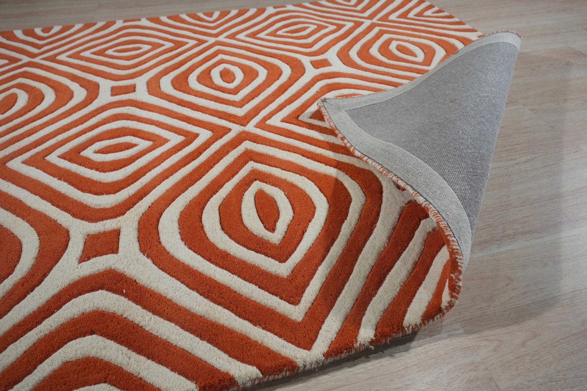 Luxurious Warm Orange Hand Tufted Wool Rug, its textured pile radiating inviting warmth, anchors a softly lit room; neutral walls and furnishings highlight the rug's rich, comforting hue.