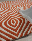 Luxurious Warm Orange Hand Tufted Wool Rug, its textured pile radiating inviting warmth, anchors a softly lit room; neutral walls and furnishings highlight the rug's rich, comforting hue.