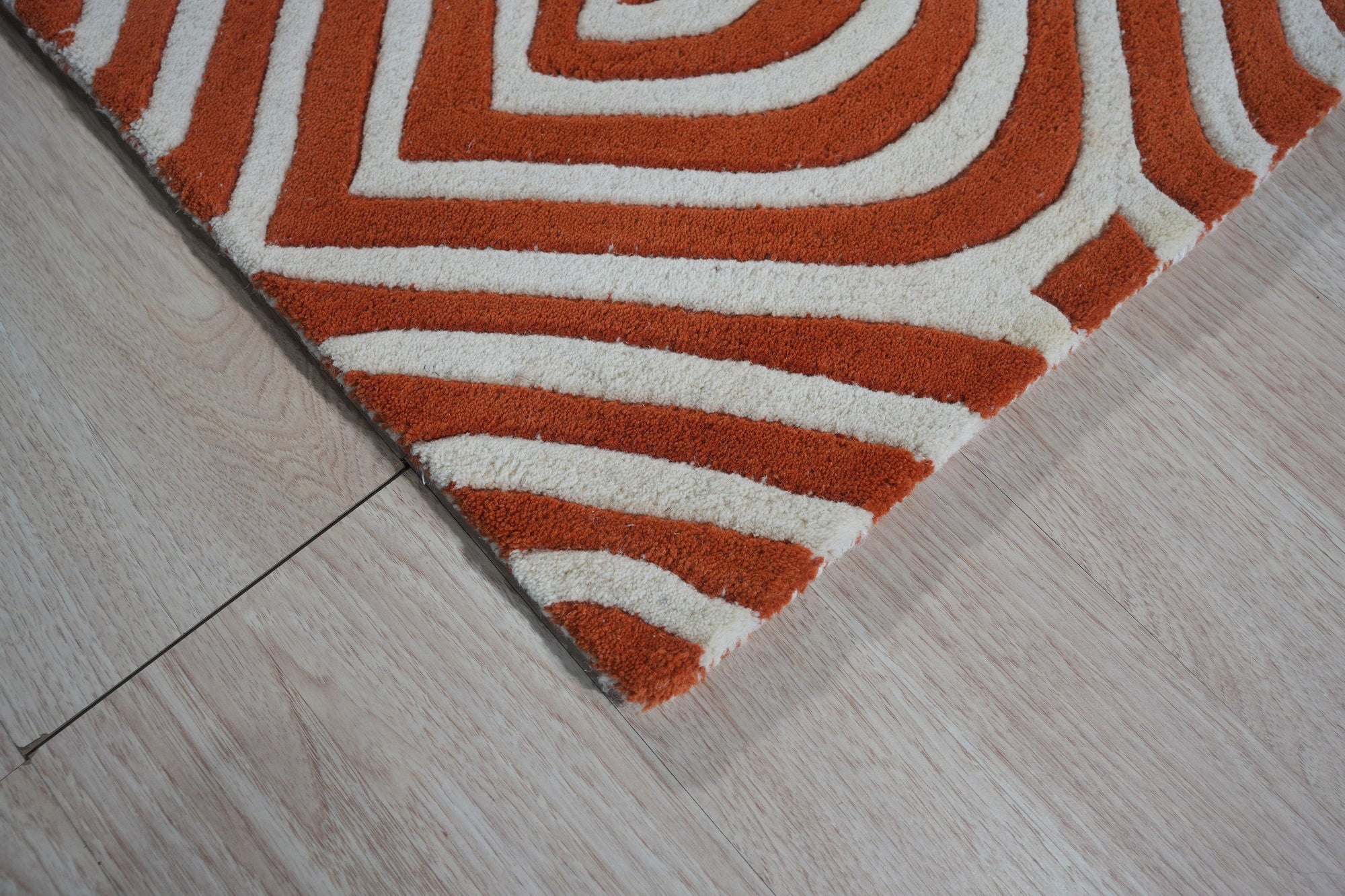 Luxurious Warm Orange Hand Tufted Wool Rug, vibrant and inviting, anchors a living space with its rich orange hue and plush texture. Hand tufted wool construction creates a dense, comfortable pile. Seen in a modern setting, complements neutral furniture with warmth and sophistication.