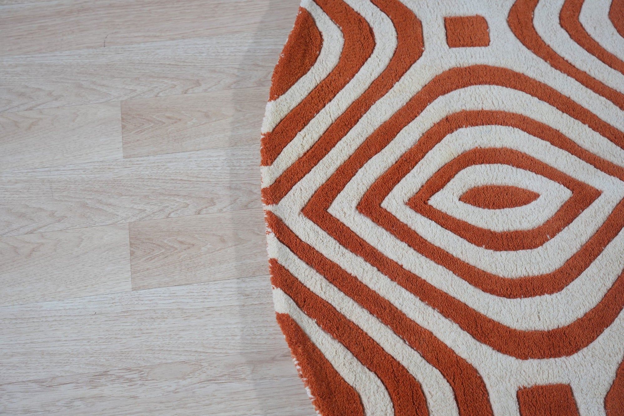 Luxurious Warm Orange Hand Tufted Wool Rug, hand-tufted in a vibrant orange hue, offers plush texture and warmth, shown in a detailed close-up revealing its construction.