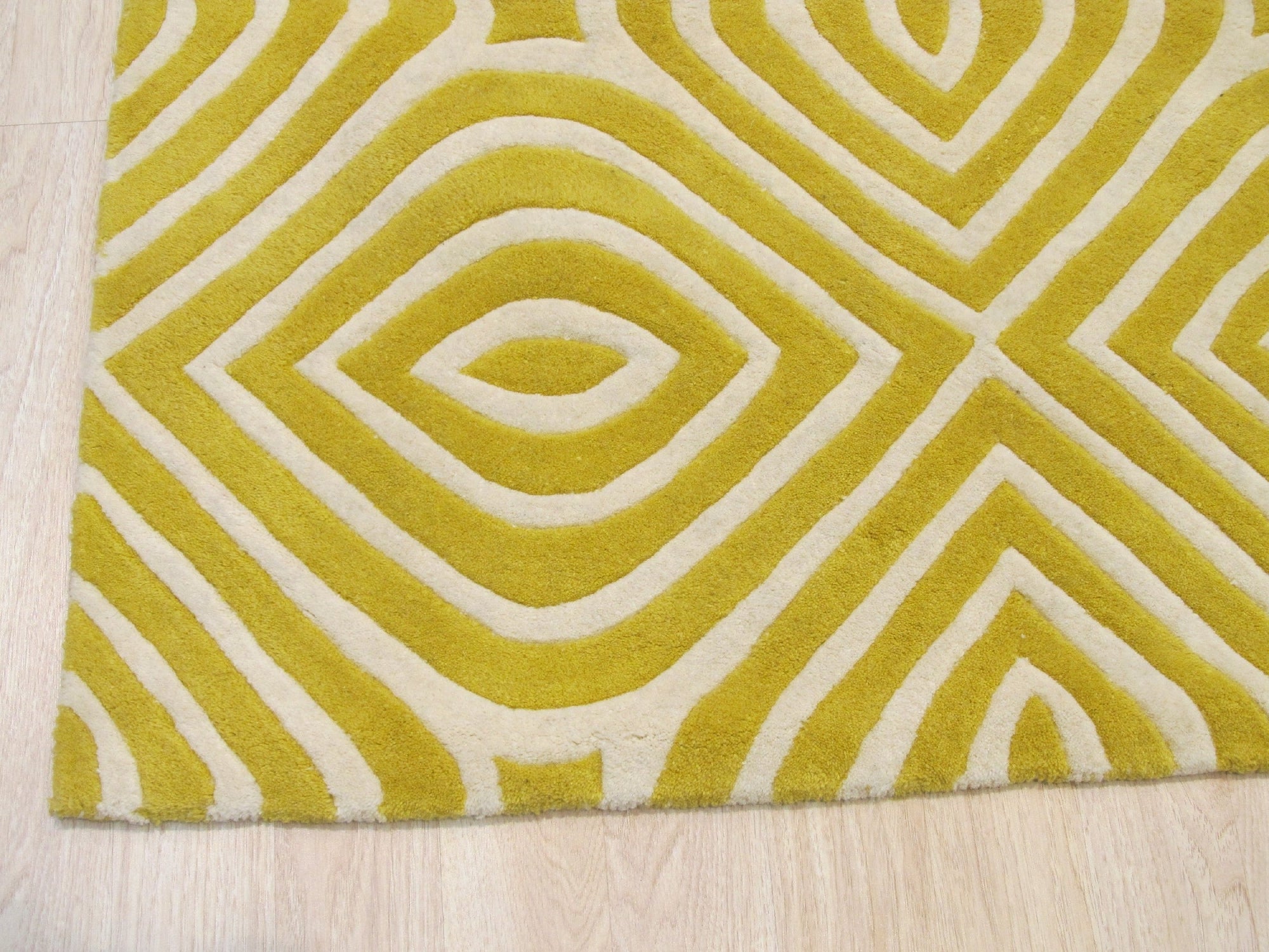 Ruby Para Yellow Hand Tufted Wool Rug, a vibrant geometric pattern in shades of ruby, yellow, and cream, graces a brightly lit living space, adding warmth and texture to the contemporary interior.