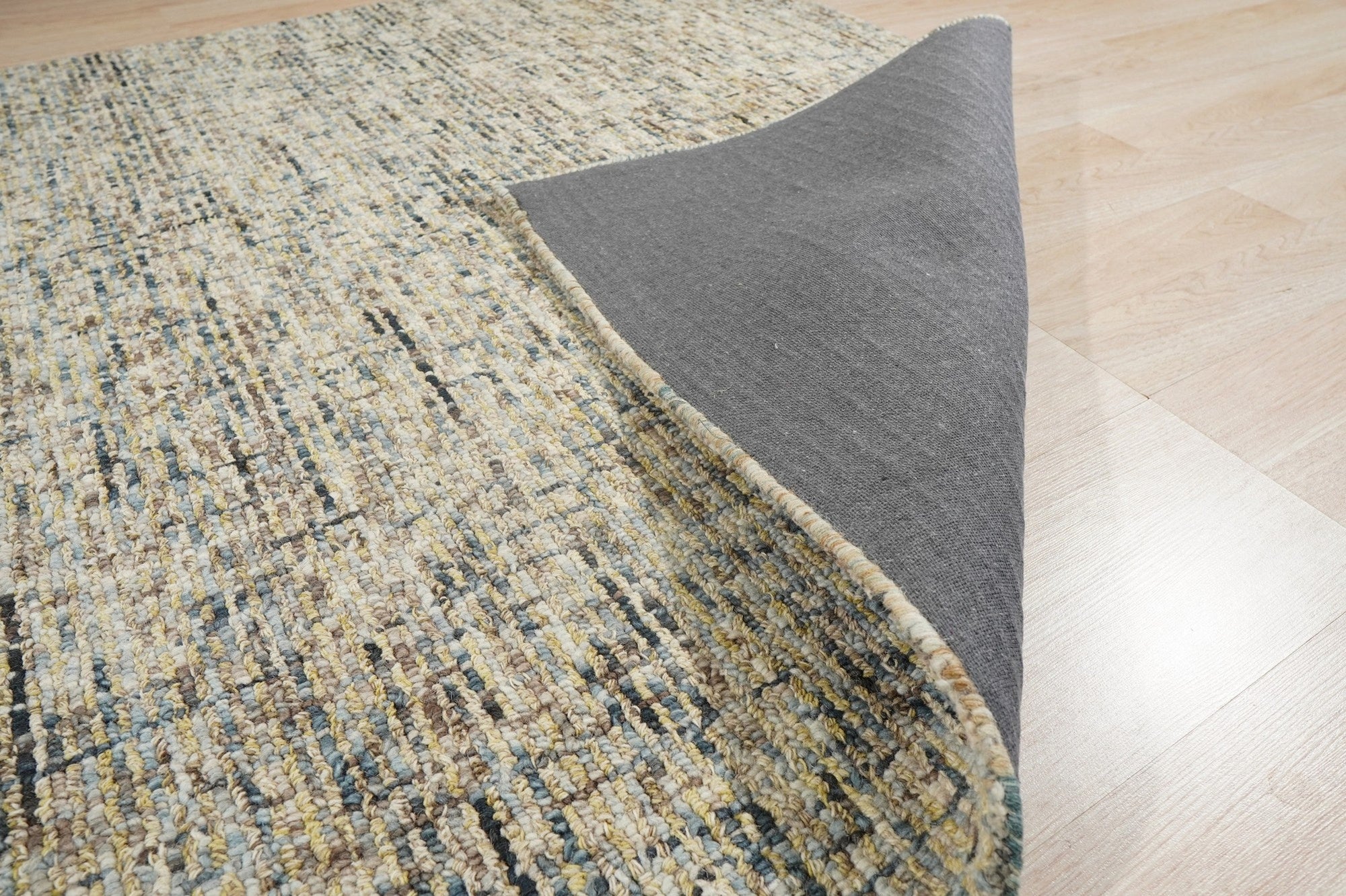Maya Bianca Navy Hand Tufted Wool Rug, showcasing a textured, modern design with intricate patterns in deep navy and contrasting ivory hues, laid out on a light hardwood floor with natural light.