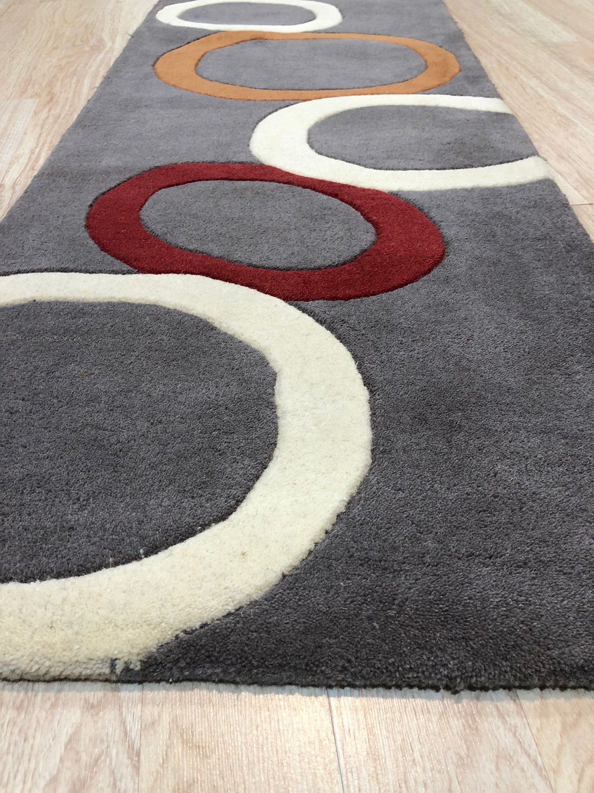 Celia Clara Gray Hand Tufted Wool Rug, a soft gray wool rug with a subtle, textured design, lying on a polished hardwood floor.