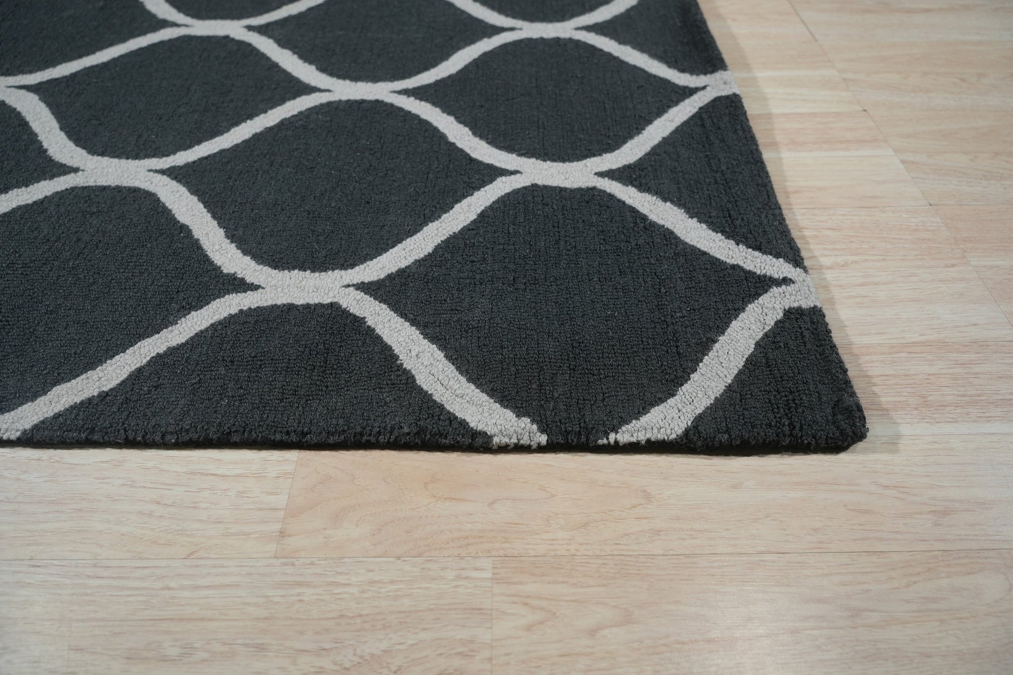 Beautiful Luna Black Hand Tufted Wool Rug, its plush texture and deep black hue grounding a contemporary living space, light subtly highlighting the hand-tufted construction.