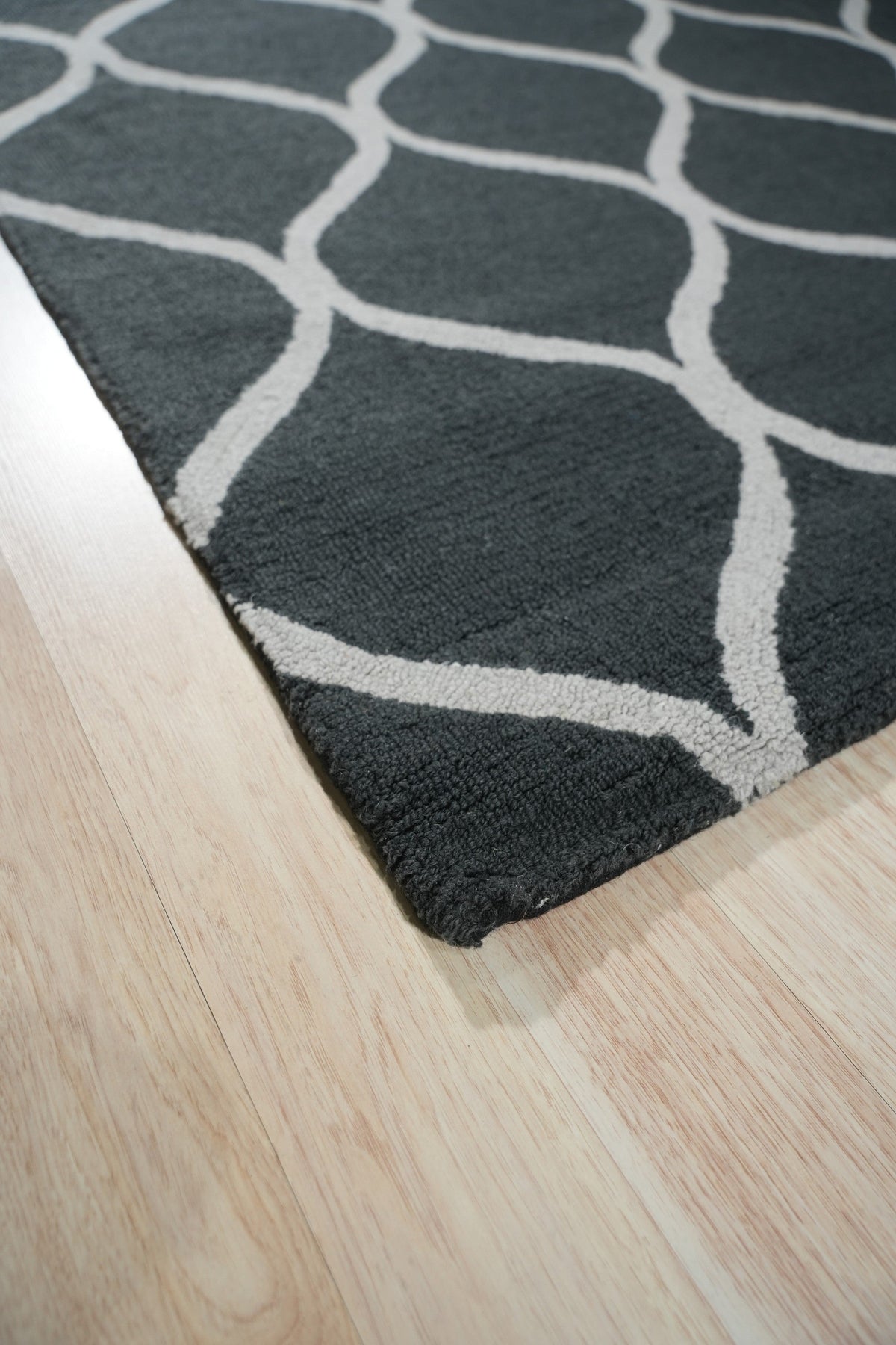 Beautiful Luna Black Hand Tufted Wool Rug, its textured black wool pile adding depth to a contemporary living room setting with neutral furniture.