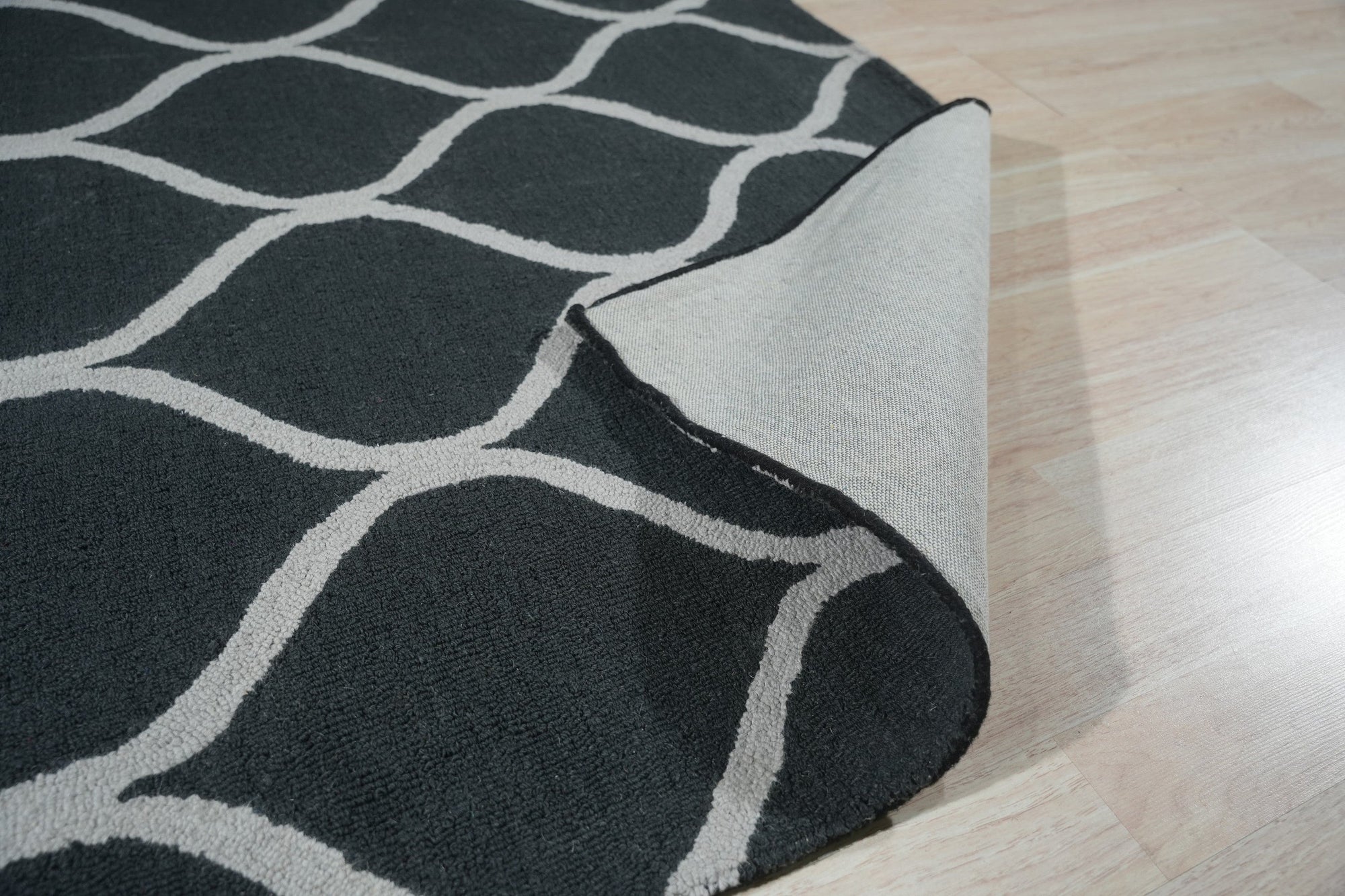 Beautiful Luna Black Hand Tufted Wool Rug, a modern statement piece under a sleek black coffee table, its textured wool contrasting with the smooth metal legs.