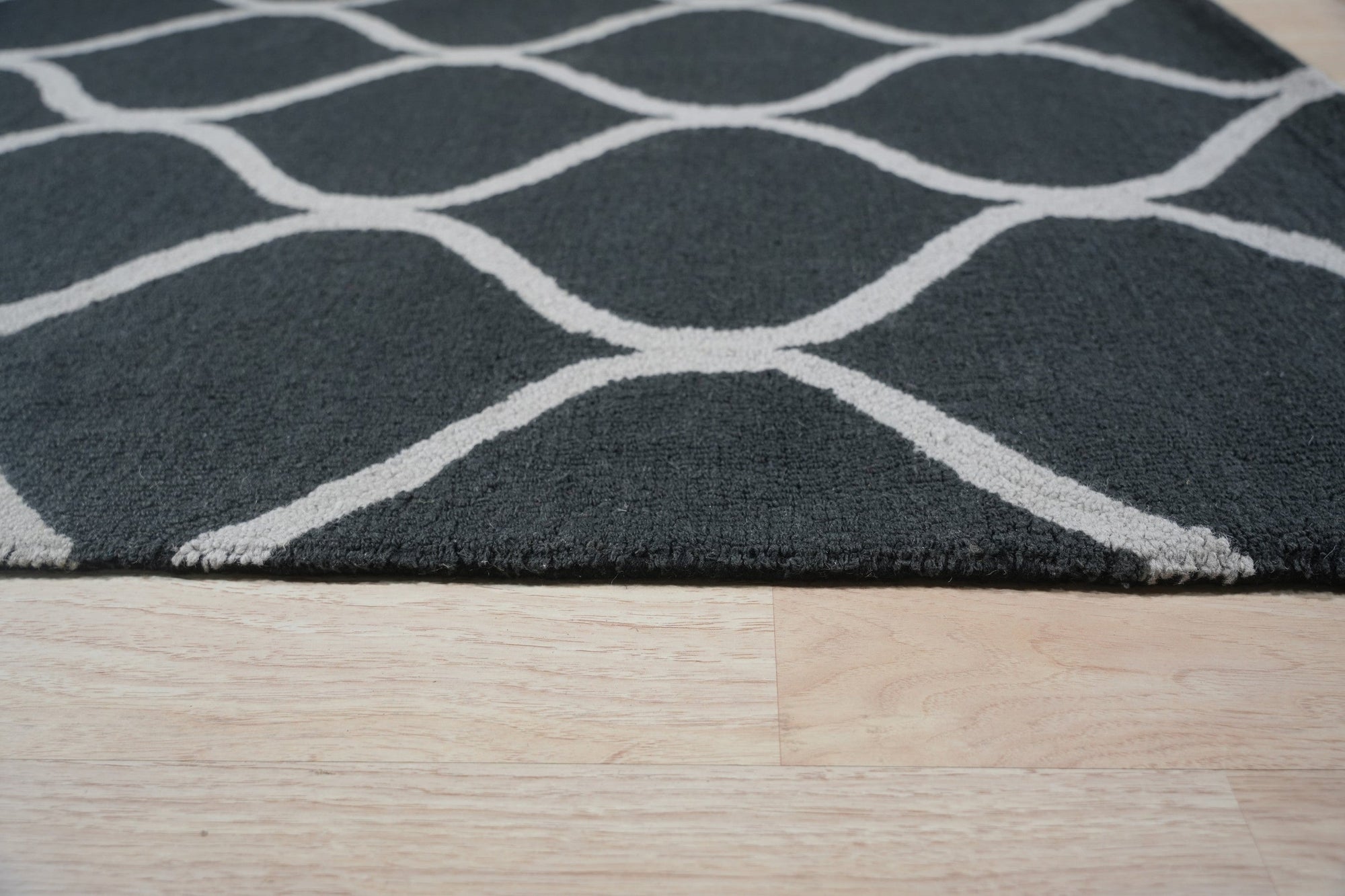 Beautiful Luna Black Hand Tufted Wool Rug, rich black wool lending depth and texture to a modern living room, its hand-tufted construction evident in the plush pile and subtle design variations underfoot.