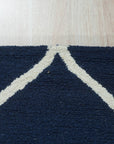 Jasmine Artisan Blue Hand Tufted Wool Rug in a bright, airy living room. Light filters across the rug's textured surface, showcasing its hand-tufted wool construction and vibrant blue hues. A comfortable seating area surrounds the rug, suggesting a cozy and inviting atmosphere.