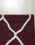 Timeless Louie Burgundy Hand Tufted Wool Rug, a rich burgundy wool rug with an ornate, traditional pattern, displayed on a light hardwood floor in a brightly lit room.