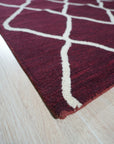 Timeless Louie Burgundy Hand Tufted Wool Rug, richly patterned, anchors a sophisticated living space. Warm light highlights the deep burgundy hues and textured hand-tufted wool, complemented by neutral furniture and hardwood floors.