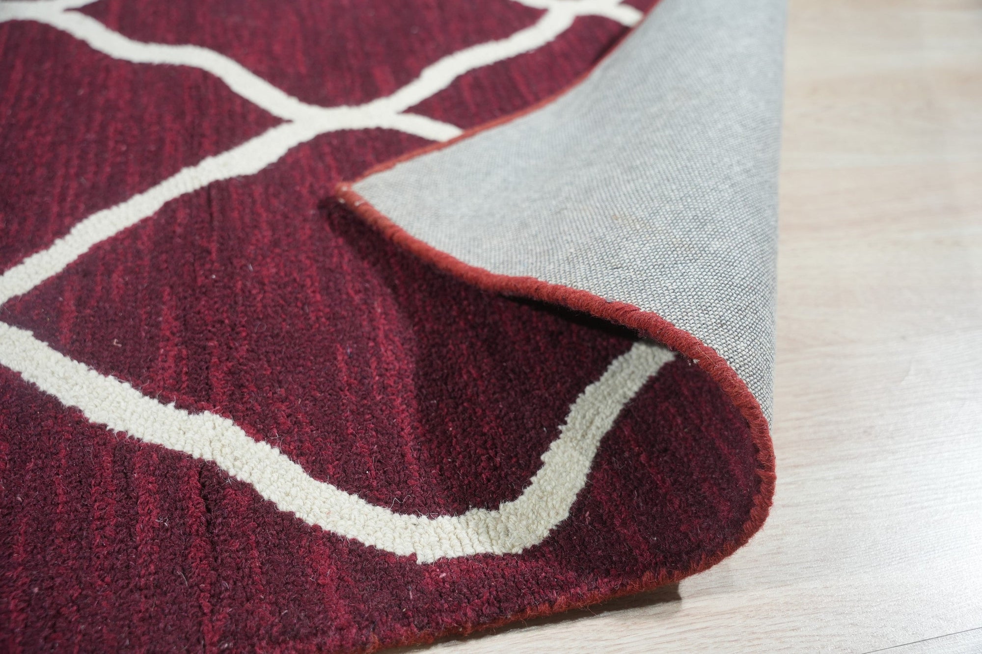 Timeless Louie Burgundy Hand Tufted Wool Rug, showcasing rich burgundy hues and intricate detailing, rests elegantly on hardwood flooring in a warmly lit room.