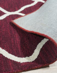 Timeless Louie Burgundy Hand Tufted Wool Rug, showcasing rich burgundy hues and intricate detailing, rests elegantly on hardwood flooring in a warmly lit room.