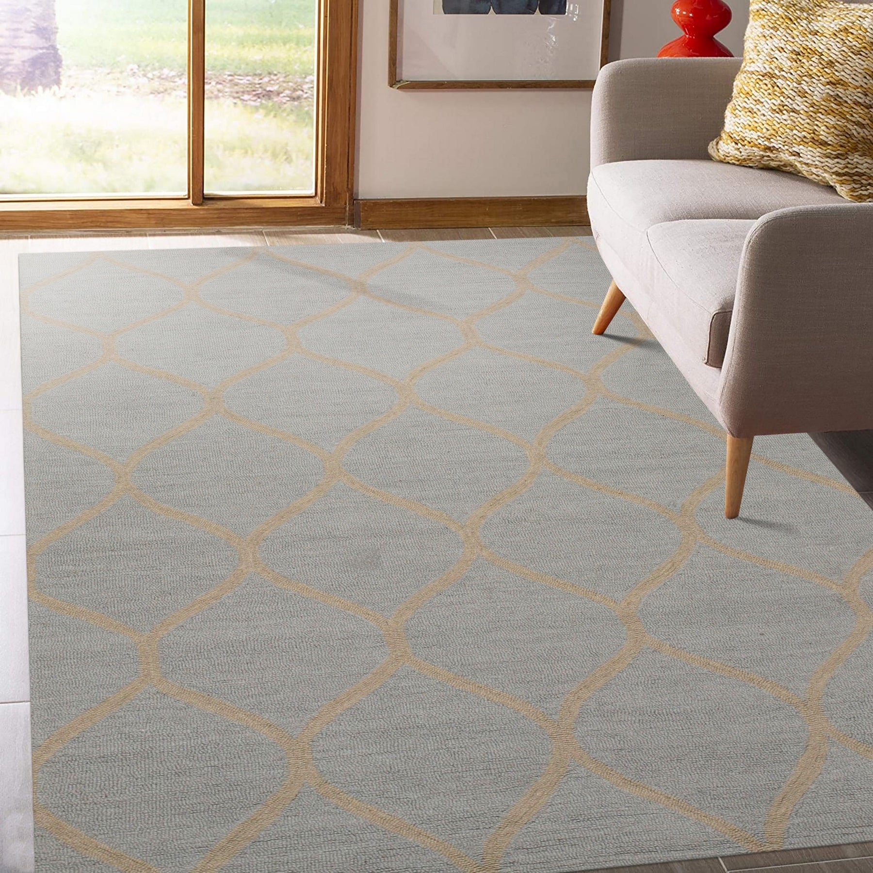 Tessa Chloe Light Blue Hand Tufted Wool Rug, a light blue wool rug with a subtle pattern, laid on a light wood floor near a sunlit window and white wall.