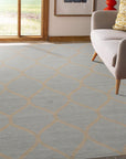 Tessa Chloe Light Blue Hand Tufted Wool Rug, a light blue wool rug with a subtle pattern, laid on a light wood floor near a sunlit window and white wall.