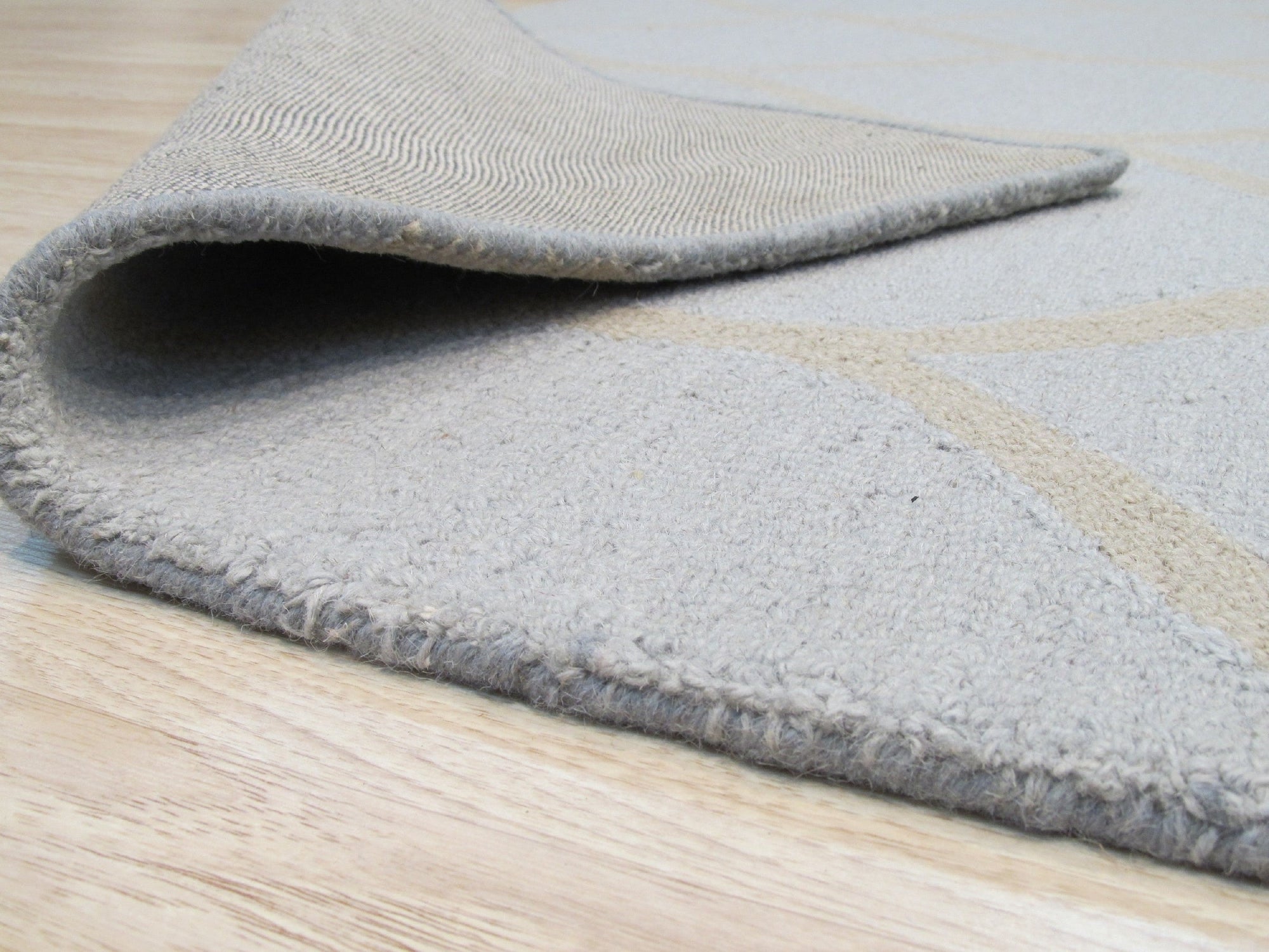 Tessa Chloe Light Blue Hand Tufted Wool Rug displayed in a bright, airy living room. Soft blues and creams dance across the wool fibers, complementing the neutral decor.