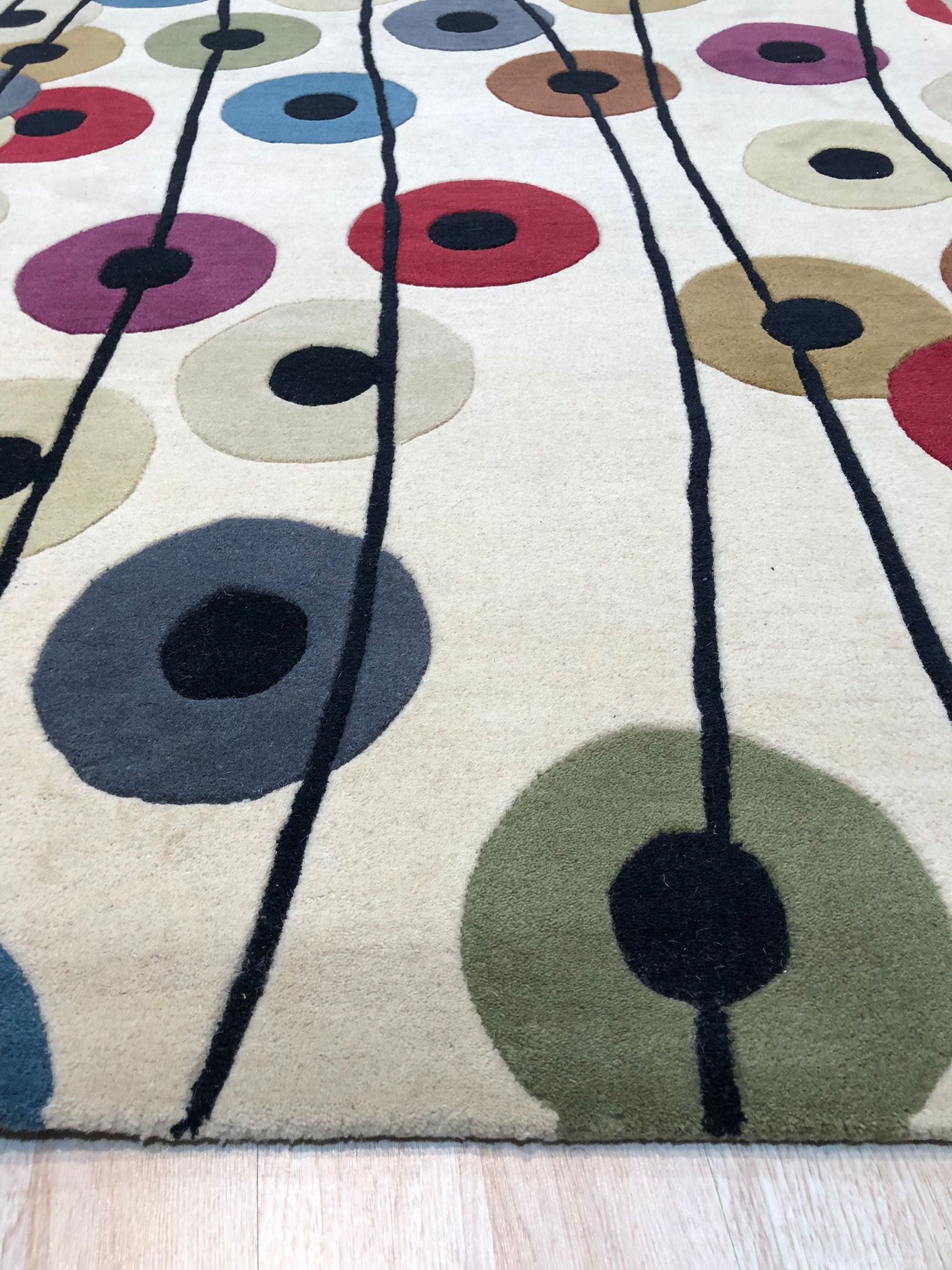 Modern Isla Multicolor Hand Tufted Wool Rug anchors a bright living space, its vibrant hues and hand-tufted texture complementing mid-century modern furniture on a light hardwood floor.