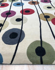 Modern Isla Multicolor Hand Tufted Wool Rug anchors a bright living space, its vibrant hues and hand-tufted texture complementing mid-century modern furniture on a light hardwood floor.