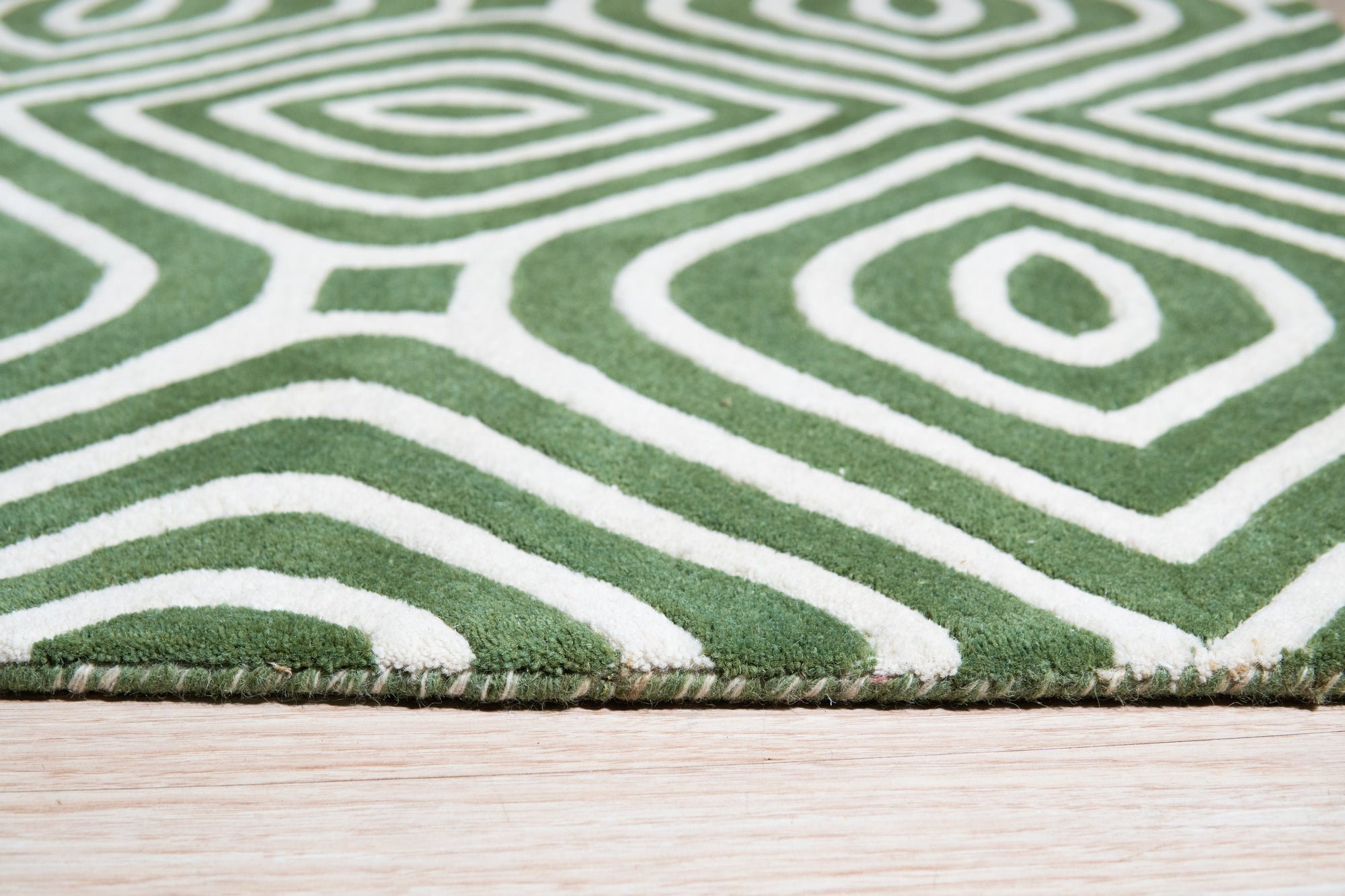 Radiant Amara Green Hand Tufted Wool Rug, showcasing lush green hues and intricate hand-tufted detailing, anchors a stylish living room setting with modern furniture and warm, inviting ambiance.