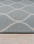 Handcrafted Laine Light Green Hand Tufted Wool Rug, a light green wool rug with a subtle geometric pattern, grounding a modern living room with warm lighting and a glimpse of a dining area beyond.