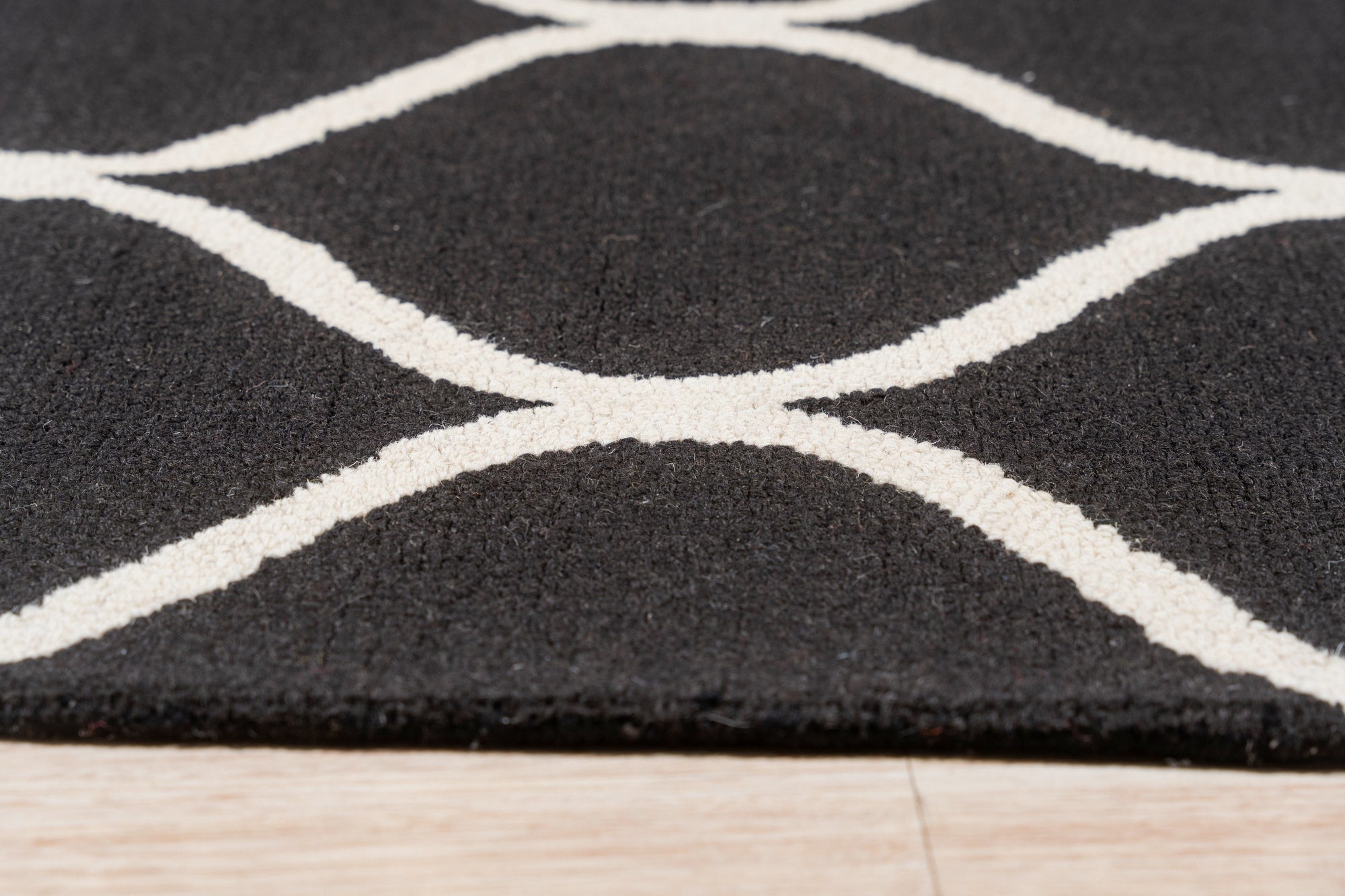 Sloane Willow Navy Hand Tufted Wool Rug anchors a living space, its deep navy hues and textural hand-tufted construction complementing light wood furniture and a cream sofa.