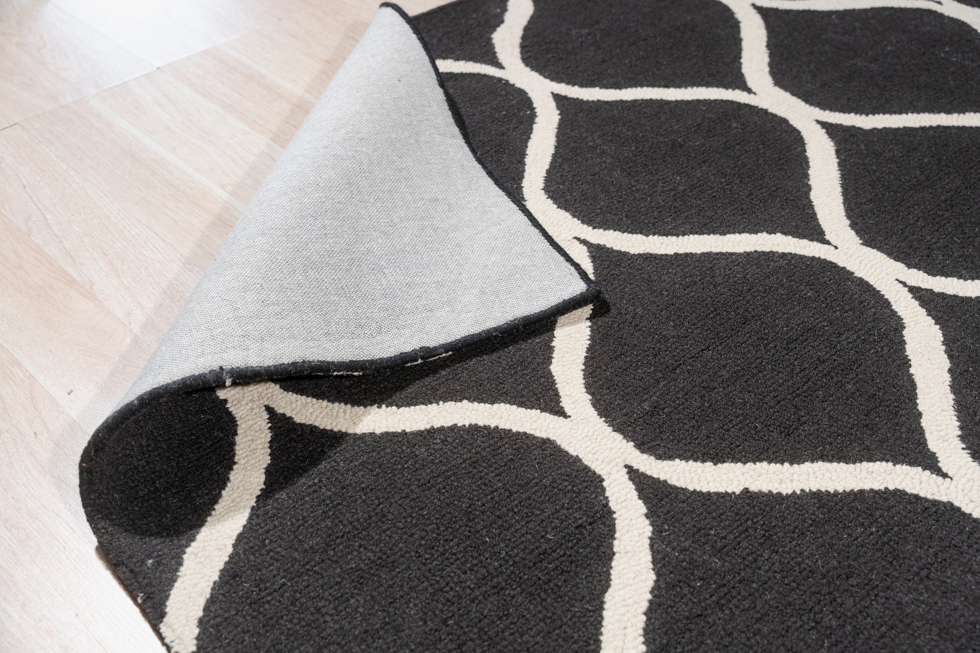 Sloane Willow Navy Hand Tufted Wool Rug, showcasing a modern living room with the rug anchoring the space. The rug features a soft, subtle willow branch design in shades of navy and ivory, its hand-tufted wool texture adding warmth and depth under a light wooden coffee table and neutral-toned sofa.