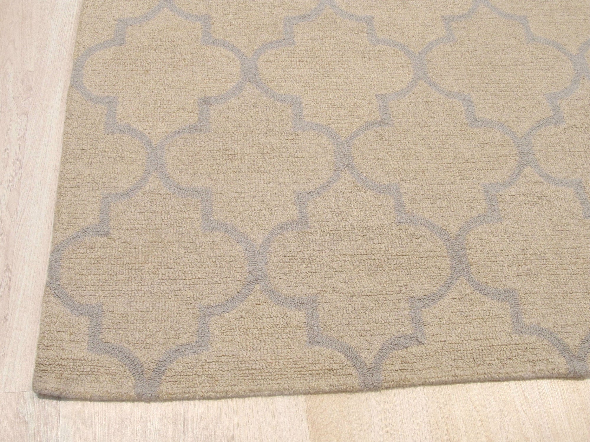 Zinnia Trellis Beige Hand Tufted Wool Rug, its delicate floral trellis pattern in soft beige tones laying grounded in a comfortably arranged living space.