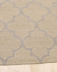 Zinnia Trellis Beige Hand Tufted Wool Rug, its delicate floral trellis pattern in soft beige tones laying grounded in a comfortably arranged living space.