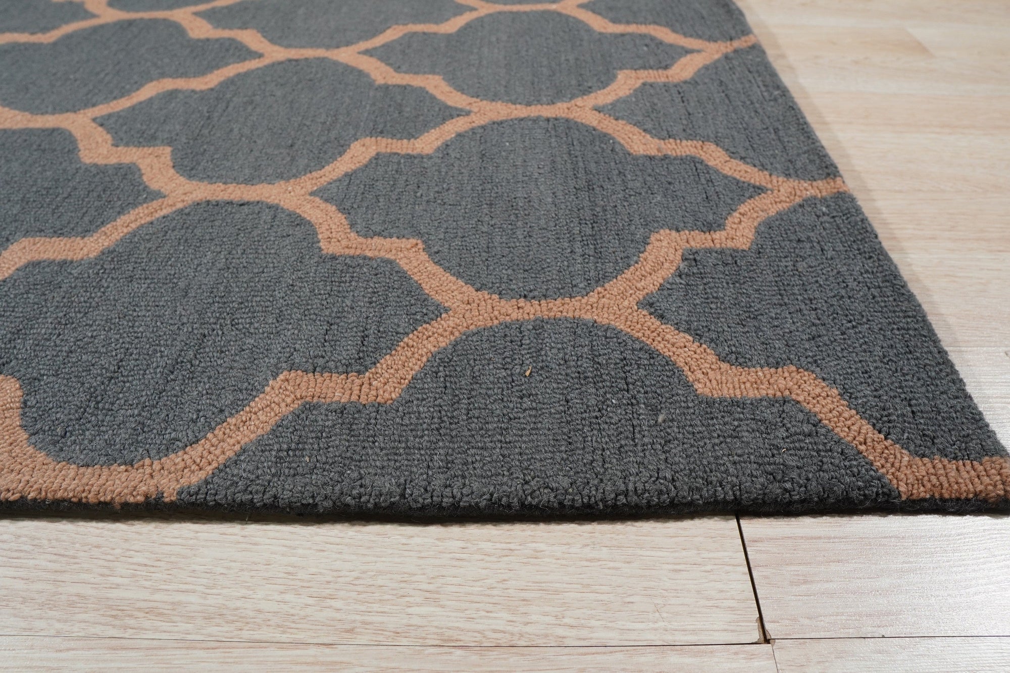 Ophelia Moroccan Midnight Hand Tufted Wool Rug, a deeply saturated midnight blue hand-tufted wool rug with an intricate Moroccan-inspired geometric pattern, rests on a light wooden floor, showcasing its texture and scale in a room setting.