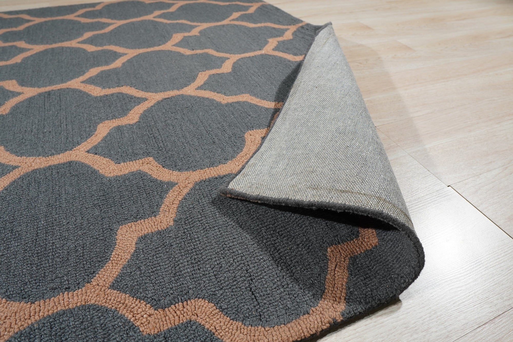 Ophelia Moroccan Midnight Hand Tufted Wool Rug, a deep midnight blue and cream wool rug featuring a geometric Moroccan-inspired design, complements a modern living room with a brown leather sofa and warm lighting.