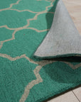 Giselle Moroccan Teal Green Hand Tufted Wool Rug, a blend of calming teal and vibrant green, graces a living room. Hand-tufted wool provides plush texture and subtle geometric Moroccan design.