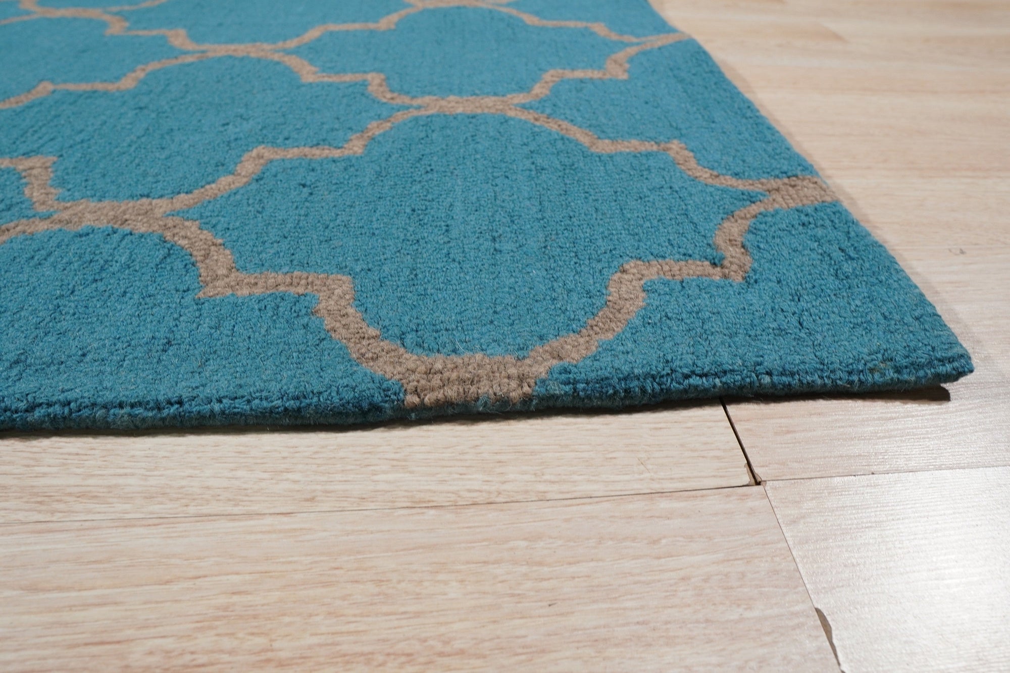 Sloane Moroccan Royal Blue Hand Tufted Wool Rug displayed within a warmly lit interior, its intricate Moroccan design and deep royal blue hues grounding the space with elegance.