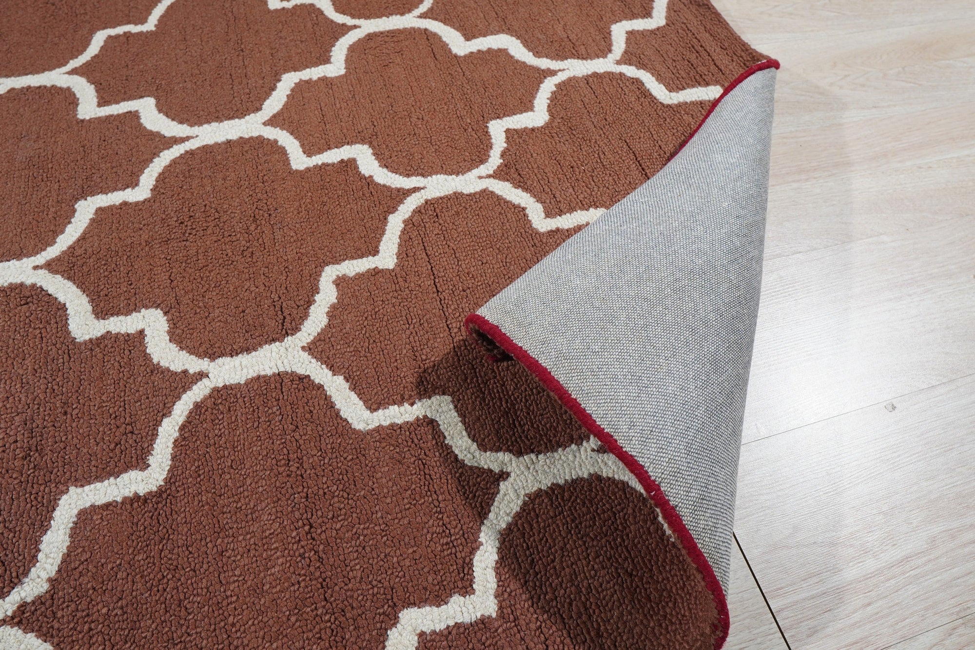 Trendy Moroccan Rust Hand Tufted Wool Rug displayed in a bright, modern living room. Warm rust tones and geometric Moroccan patterns accent the space. Hand-tufted wool construction offers visible texture and depth underfoot.