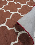 Trendy Moroccan Rust Hand Tufted Wool Rug displayed in a bright, modern living room. Warm rust tones and geometric Moroccan patterns accent the space. Hand-tufted wool construction offers visible texture and depth underfoot.