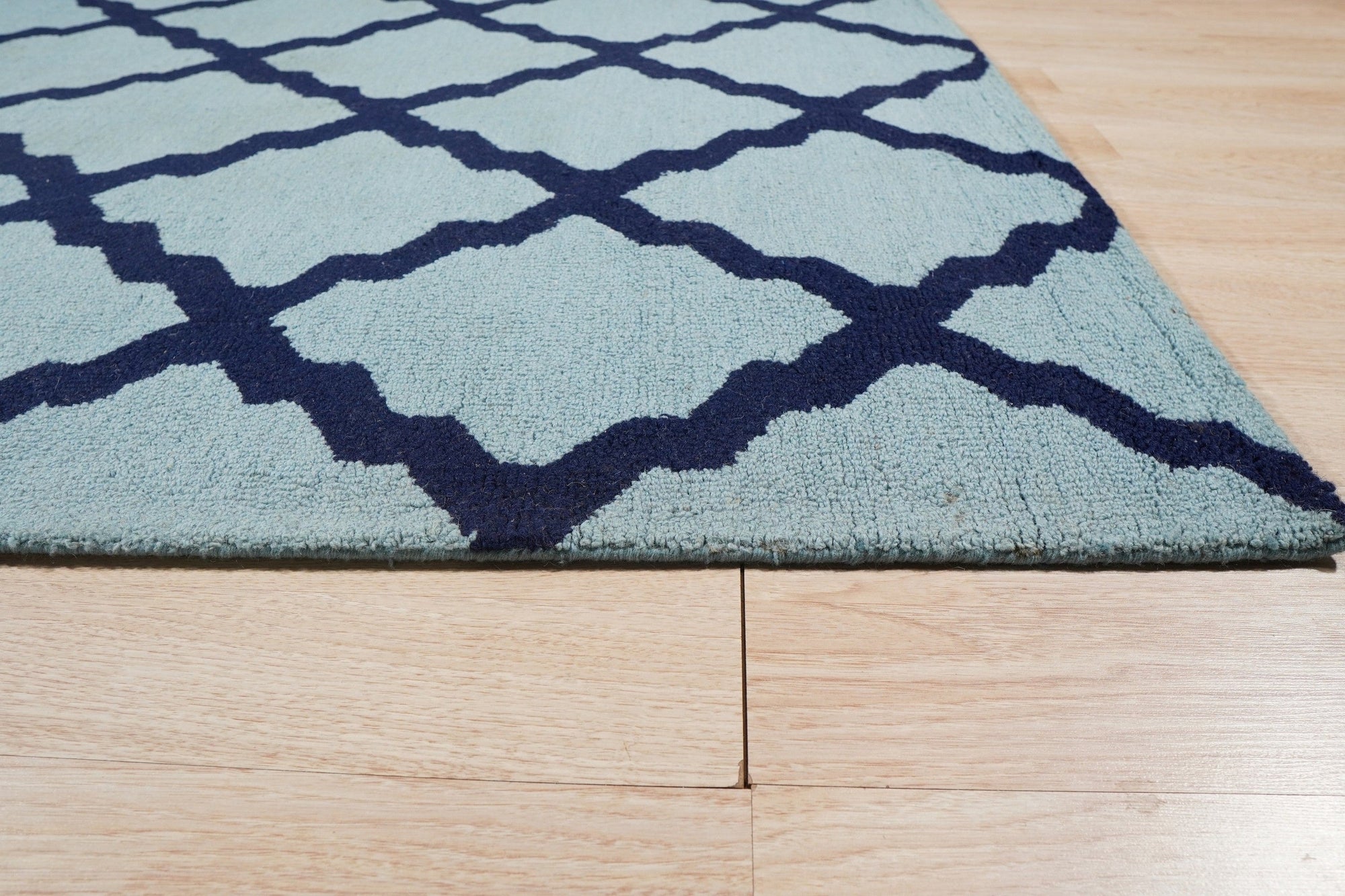 Bianca Trellis Sea Blue Hand Tufted Wool Rug, showcasing its cool sea blue hue and intricate trellis pattern in a room setting.