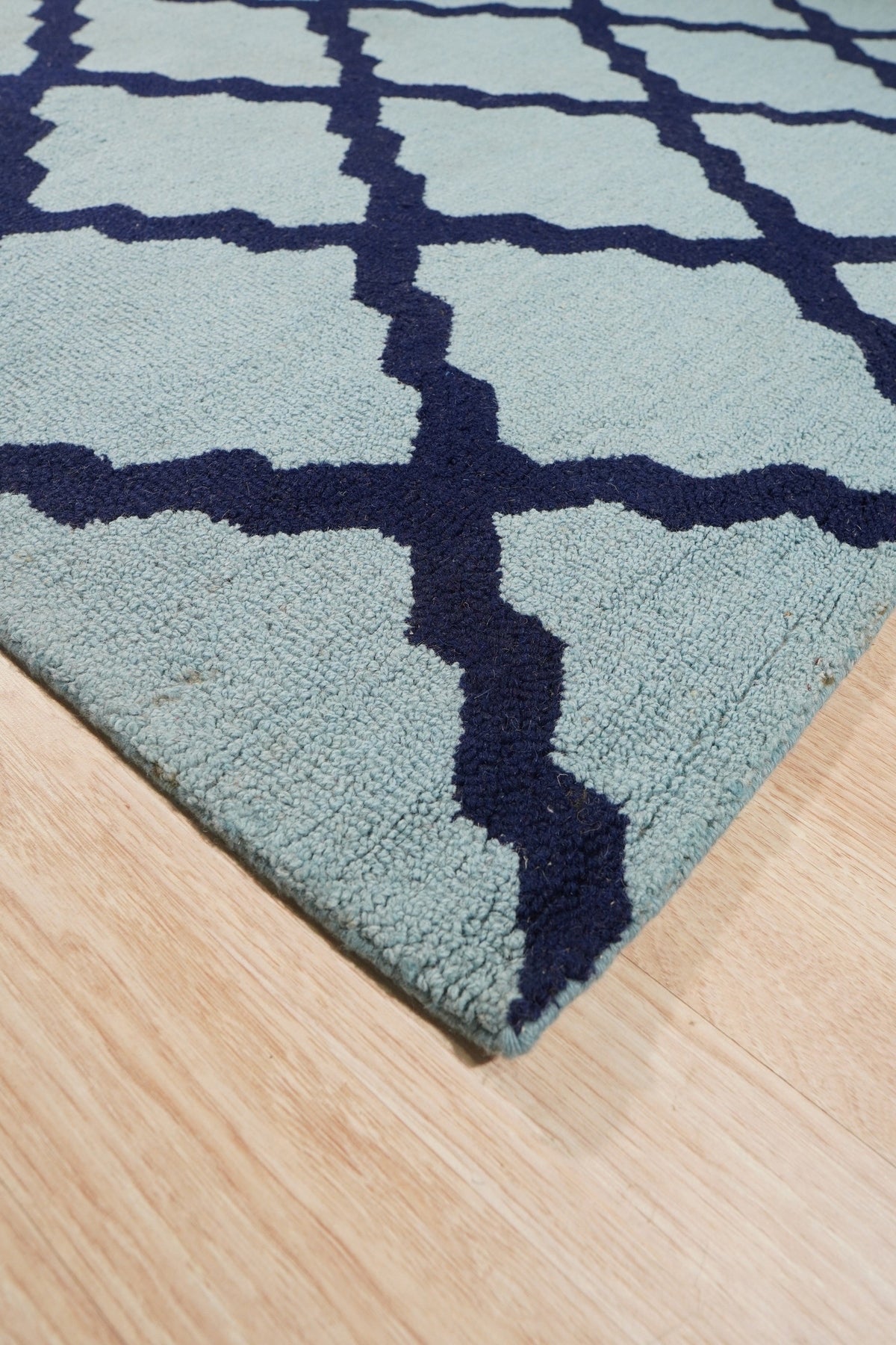 Bianca Trellis Sea Blue Hand Tufted Wool Rug, a soft sea blue wool rug featuring a classic trellis pattern, laid on a light wood floor creating a soothing and inviting atmosphere.