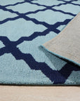 Bianca Trellis Sea Blue Hand Tufted Wool Rug, featuring a delicate trellis pattern in varying shades of sea blue, graces a softly lit room, adding texture and subtle elegance to the space.