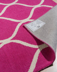 Willow Ella Pink Hand Tufted Wool Rug, displaying soft pink hues and a subtle, textured pattern, layered in a bright, naturally lit room with neutral furniture and hardwood flooring.