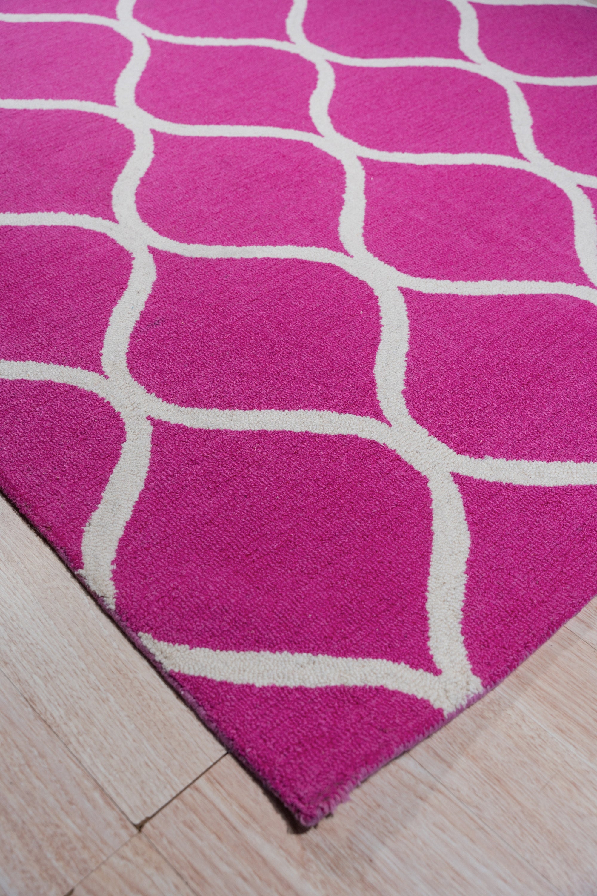 Willow Ella Pink Hand Tufted Wool Rug, a plush pink wool rug with a swirling, abstract floral design, seen in a bright, airy living room setting.