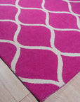 Willow Ella Pink Hand Tufted Wool Rug, a plush pink wool rug with a swirling, abstract floral design, seen in a bright, airy living room setting.